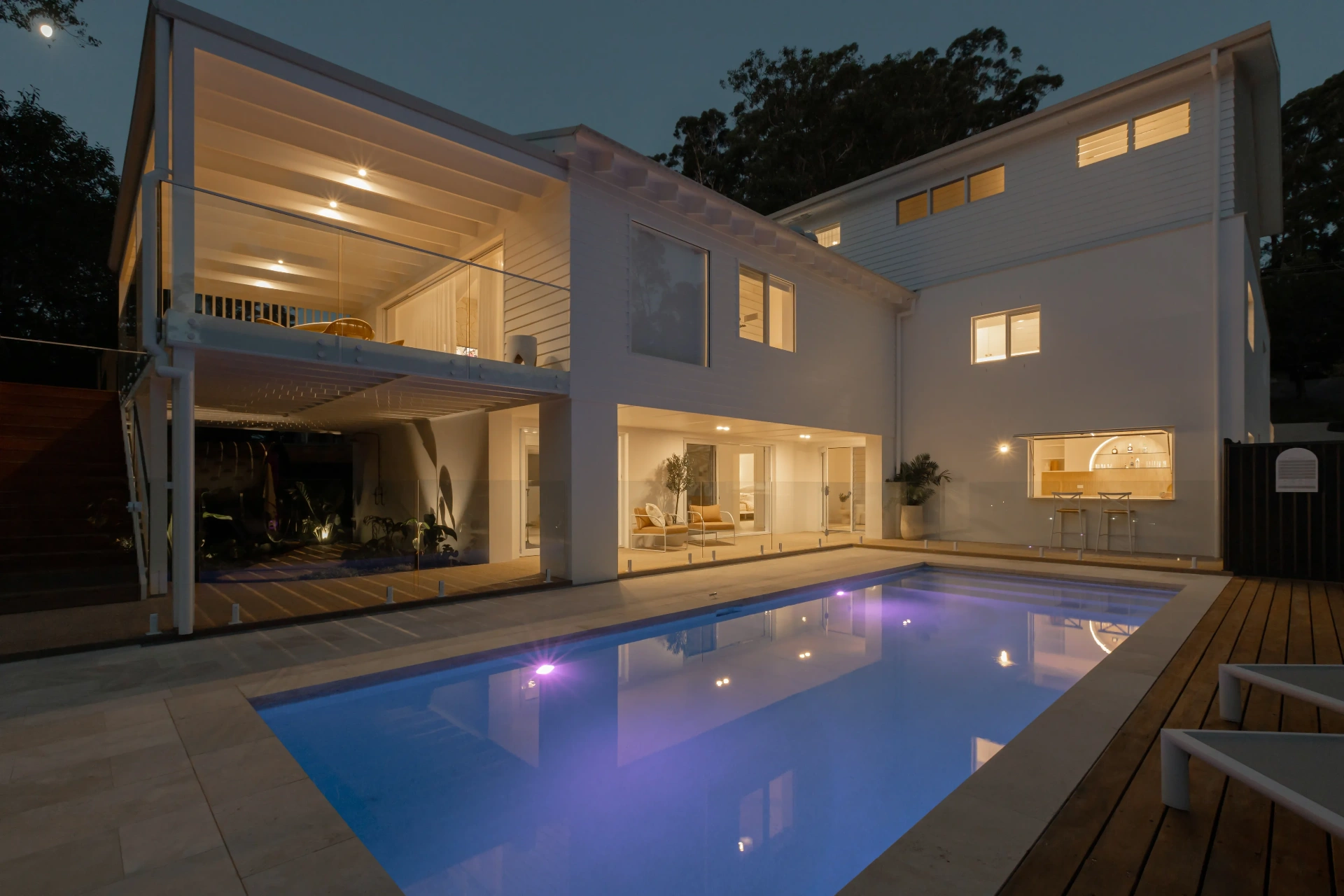 Pool and home at dusk with feature pool and facade lighting